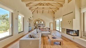 A spacious living area with a wooden ceiling, a sofa set, a coffee table, and a fireplace. - Villa Marat - Four Bedroom Villa, Sleeps 8 (Astratigos)