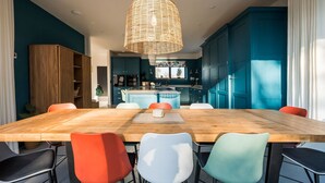 A modern kitchen with teal cabinetry, a central island, and a hanging wicker light fixture. - Elysian Heights - Five Bedroom Villa, Sleeps 10 (Cheltenham)