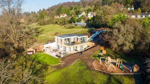 A modern house with a large deck, a swimming pool, and a playground. - Elysian Heights - Five Bedroom Villa, Sleeps 10 (Cheltenham)