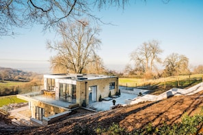 Une maison moderne dotée d’une façade en verre, d’un toit plat et d’un espace patio.