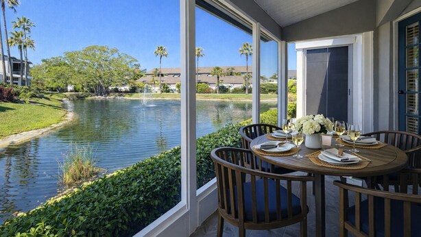 A dining area with a view of a lake, surrounded by greenery and palm trees. - ALL NEW - Resort Amenities and Beach Access (Siesta Key)