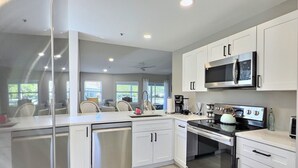 A modern kitchen with white cabinetry, a stainless steel dishwasher, an oven, and a microwave. - ALL NEW - Resort Amenities and Beach Access (Siesta Key)