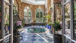 A sunlit courtyard with a pool, brick walls, arched windows, and potted plants. - Greenwich Hall - Nine Bedroom Villa, Sleeps 22 (London)