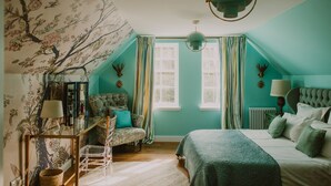 Um quarto com uma cama, uma cadeira, uma escrivaninha e uma janela.