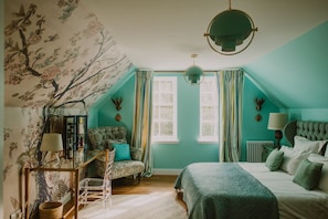 Ein Schlafzimmer mit einem Bett, einem Sessel, einem Schreibtisch und einem Fenster.