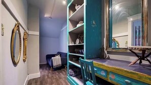 Ein Zimmer mit Holzboden, einem smaragdgrünen Schreibtisch mit Schubladen, einem Stuhl und einem großen Spiegel.