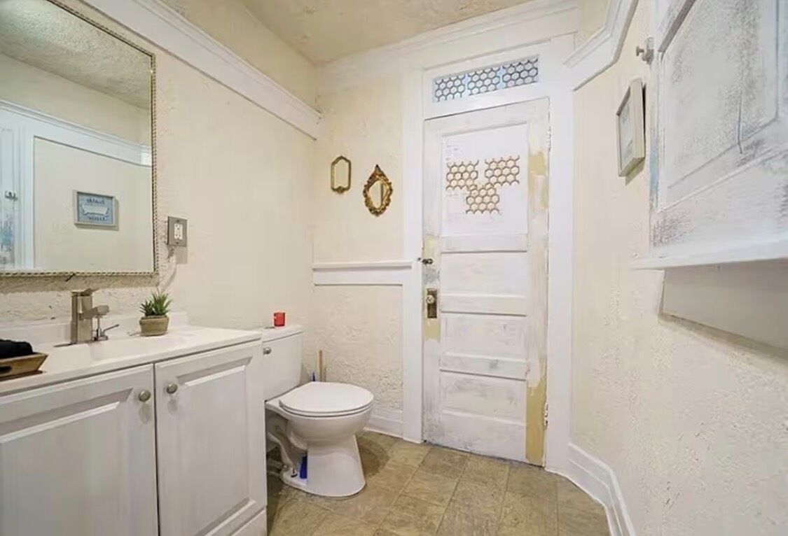 Et badeværelse med toilet, håndvask og spejl.