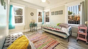 Ein Schlafzimmer mit Bett, Sessel, Nachttisch, Deckenventilator und Fenster.