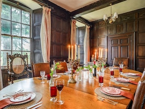 A dining room with a wooden table set for a meal, candle-lit ambiance, and large windows.
