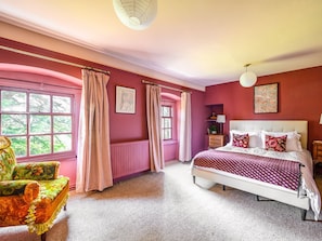 A bedroom with a bed, a chair, a window, and a radiator.