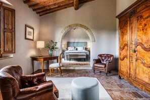 A bedroom with a bed, a wooden cabinet, a leather armchair, a small table with a lamp, and a vase with flowers. - Casale Eleganza - Five Bedroom Villa, Sleeps 10 (San Gimignano)