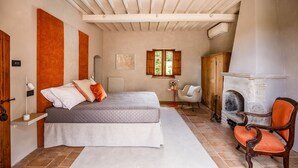 Ein Schlafzimmer mit einem Bett, einem Sessel, einem Kamin und einem Fenster.