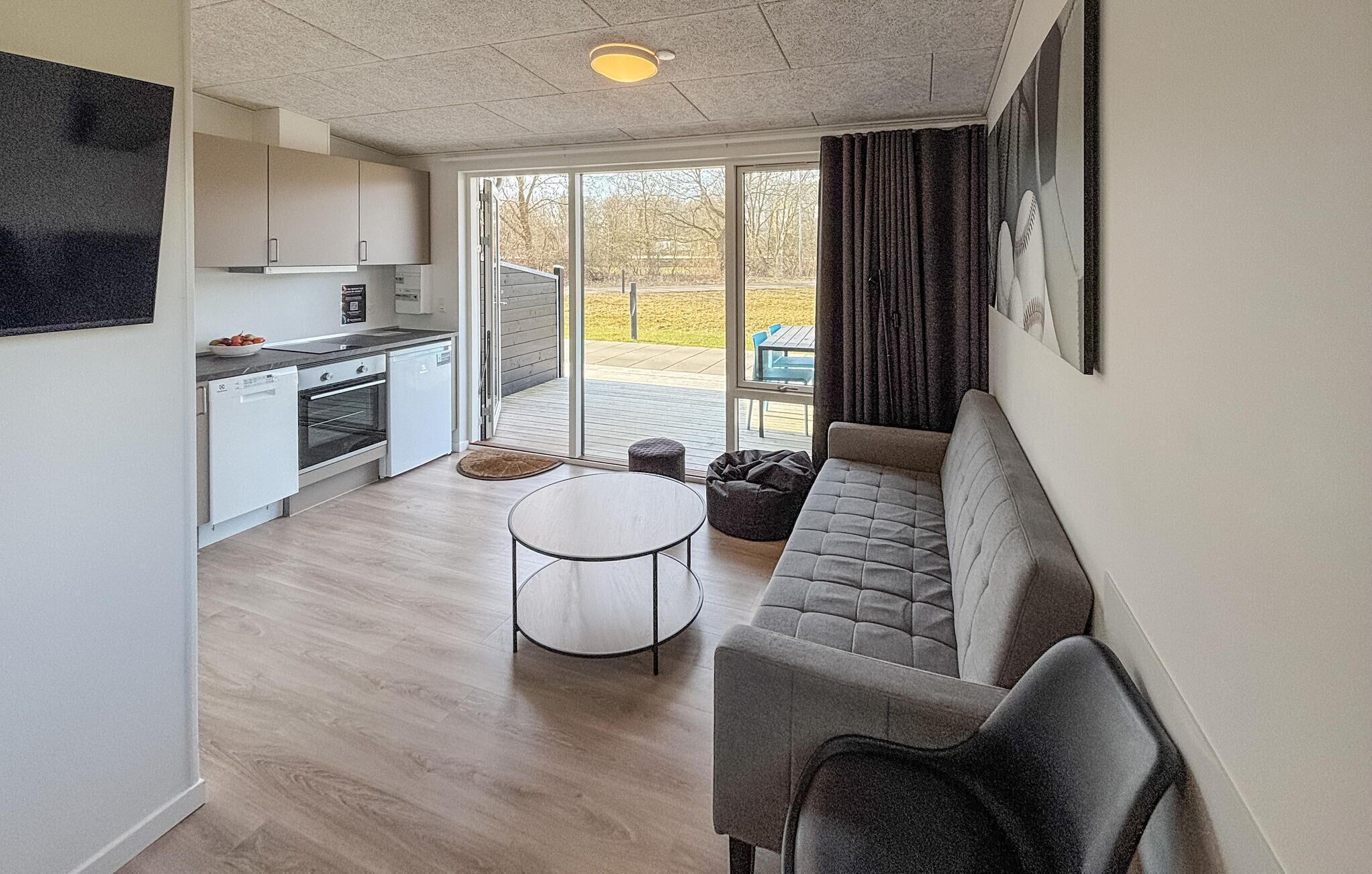 A modern kitchen with white cabinets, a dining table, and a grey sofa.