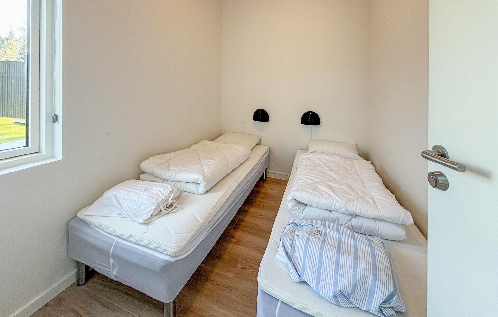 A small, clean room with two single beds, a window, and a door.