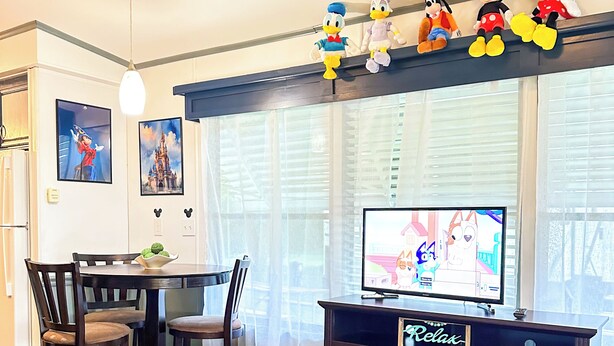 Una sala de estar con chimenea, una mesa de comedor con sillas, un televisor y peluches en la repisa.