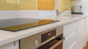 Uma cozinha moderna com armários brancos, forno embutido e bancada com pia.
