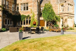 A stone building with a courtyard patio, outdoor seating, and a staircase leading to an upper level. - Baronial Mansion - Five Bedroom Villa, Sleeps 10 (Alness)