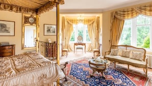 Une chambre dotée d’un lit à baldaquin, d’un canapé, d’une table et offrant une vue par la fenêtre.