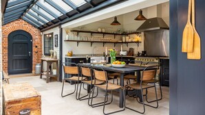Una cocina con una mesa de comedor, sillas y diverso menaje de cocina.
