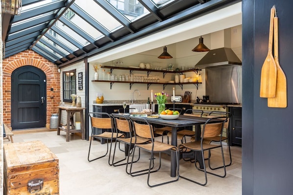 A kitchen with a dining table, chairs, and a variety of kitchenware.