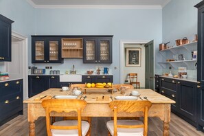 Une cuisine avec des meubles de rangement de couleur sombre, une table à manger en bois et un coin repas pour le petit-déjeuner.