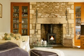 A cozy living room with a stone fireplace, a bookshelf, and a comfortable sofa.