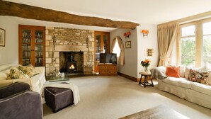 A cozy living room with a stone fireplace, a television, and a sofa. - Abbeville Barn - Four Bedroom Villa, Sleeps 11 (Langford)