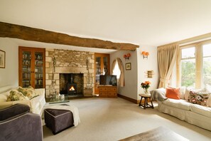 A cozy living room with a stone fireplace, a television, and a sofa.
