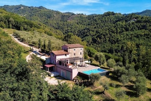 A two-story stone house with a swimming pool, surrounded by dense forest and hills. - Villa Eveo - Four Bedroom Villa, Sleeps 7 (Marliana)