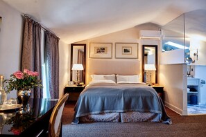 A hotel room with a bed, bedside lamps, a mirror, a dresser, a vanity, and a vase with flowers. - Villa Eveo - Four Bedroom Villa, Sleeps 7 (Marliana)