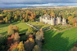 A large, historic building with a formal garden and a moat.