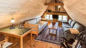 Ein gemütliches Loft-Zimmer mit Holzvertäfelung, einer Couch, einem Tisch und einem Fernseher.