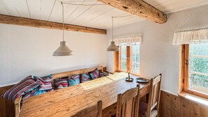 Eine rustikale Holzbank mit Sitzfläche, zwei Pendelleuchten und ein Fenster mit Blick ins Grüne.