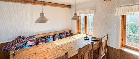 A rustic wooden bench with a bench seat, two pendant lights, and a window with a view of greenery.