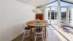 Ein Essbereich mit einem runden Tisch, weißen Stühlen und einer Deckenleuchte.
