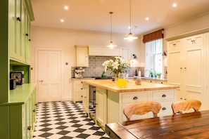 A kitchen with a checkered floor, a coffee machine, and a vase with flowers on the island. - Freya House - Nine Bedroom Villa, Sleeps 18 (Nairn)