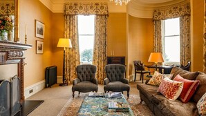 A traditional room with a fireplace, two armchairs, a sofa, and a patterned rug. - Freya House - Nine Bedroom Villa, Sleeps 18 (Nairn)