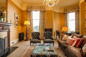 A traditional room with a fireplace, two armchairs, a sofa, and a patterned rug. - Freya House - Nine Bedroom Villa, Sleeps 18 (Nairn)