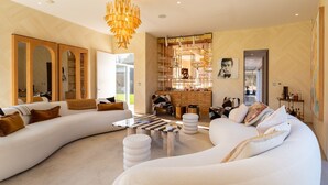 A modern living room with a large white sectional sofa, a glass coffee table, and a decorative chandelier. - Stardust Mansion - Six Bedroom Villa, Sleeps 12 (Milford)