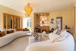 A modern living room with a large white sectional sofa, a glass coffee table, and a decorative chandelier.