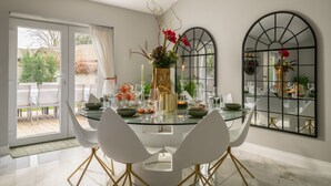 A dining area with a glass table, white chairs, and a vase with flowers. - Clarence Estate - Eight Bedroom Villa, Sleeps 20 (Woodnesborough)
