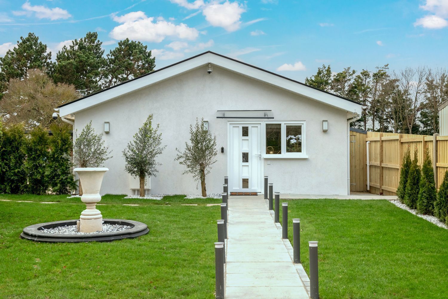 A modern single-story building with a white exterior, a front door, and a small porch.