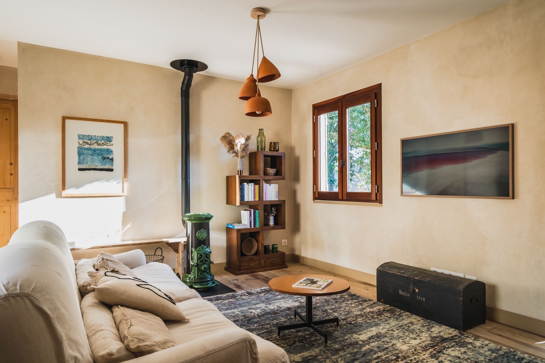 Ein Wohnzimmer mit einer Couch, einem Bücherregal, einem Tisch und einem Fenster.