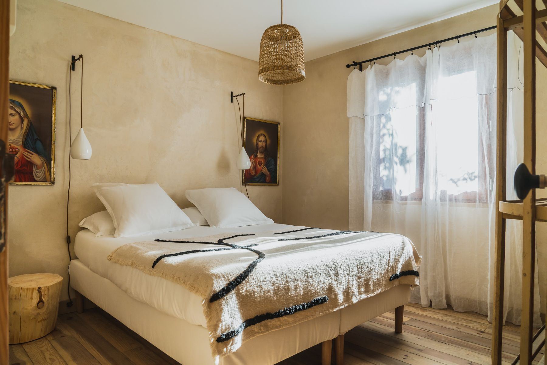 Ein Schlafzimmer mit einem Bett, zwei Wandlampen, einer Pendelleuchte und zwei Bildern.