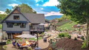 A two-story house with a patio area featuring a fire pit and outdoor seating. - True Blue 92 at Eagles Nest - 3 King Suites, Deck Fire Table, Firepit (Banner Elk)