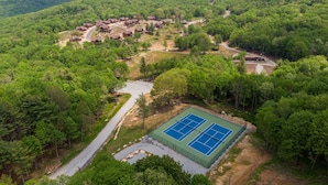 A hilly area with a cluster of cabins and a tennis court. - True Blue 92 at Eagles Nest - 3 King Suites, Deck Fire Table, Firepit (Banner Elk)