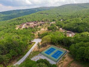 A hilly area with a cluster of cabins and a tennis court. - True Blue 92 at Eagles Nest - 3 King Suites, Deck Fire Table, Firepit (Banner Elk)