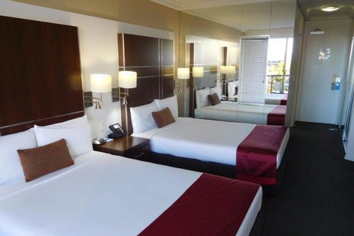 Ein Hotelzimmer mit zwei Betten, einem Nachttisch mit Telefon und einem Spiegel.