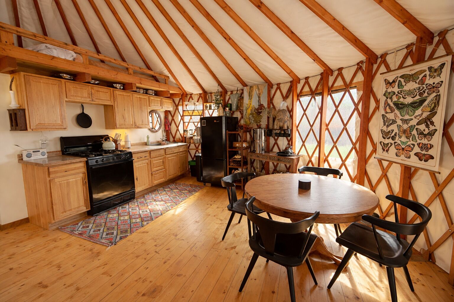 A tented accommodation with a kitchen, dining area, and a butterfly art piece.