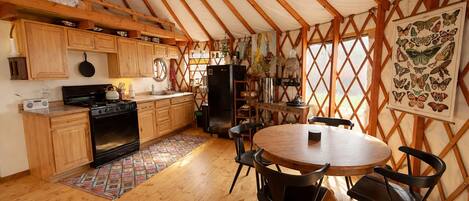 A tented accommodation with a kitchen, dining area, and a butterfly art piece.
